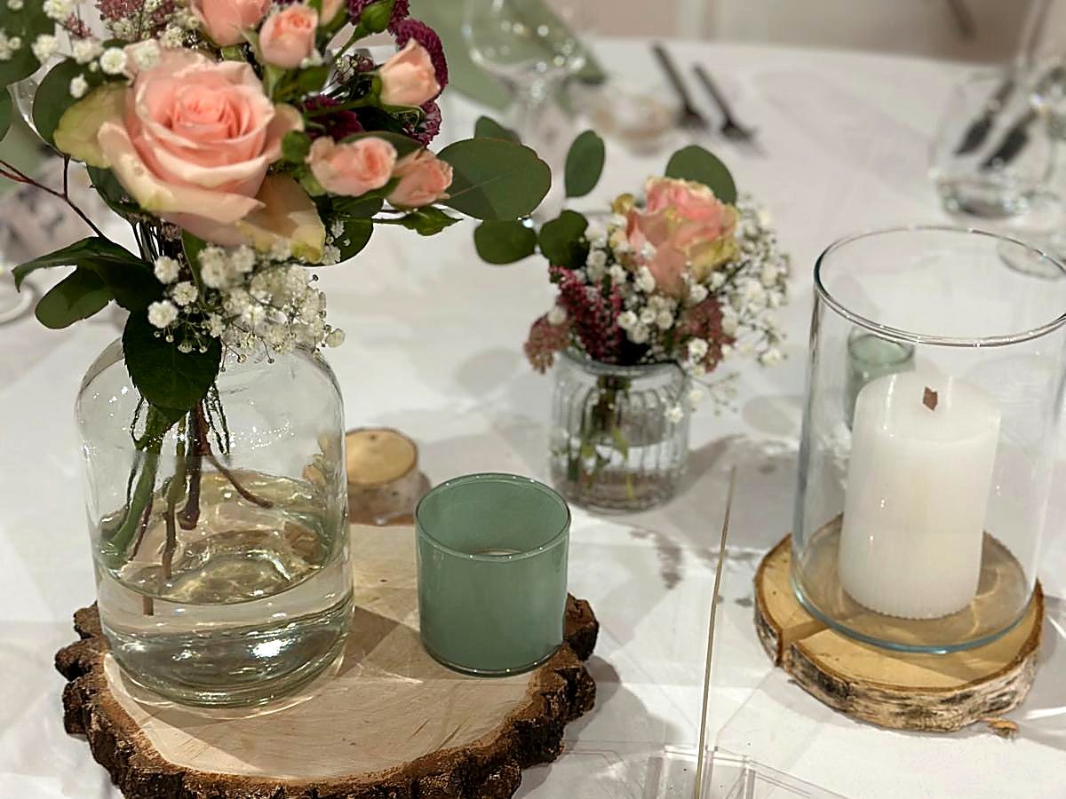 Tischdekoration mit Rosen, Astilbe und Windlicht auf einer Baumscheibe
