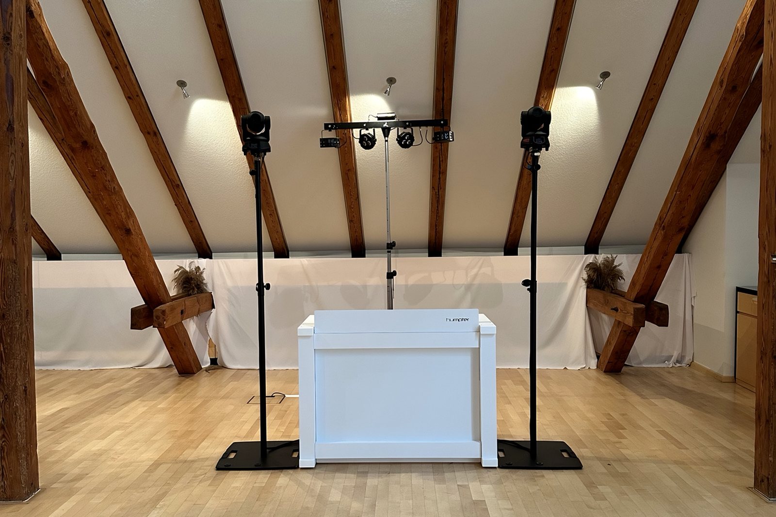 DJ-Pult mit Moving Heads und Lautsprechern in einem Saal mit Holzdachstuhl